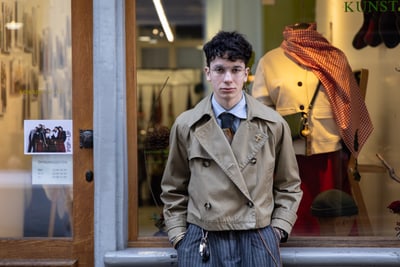 Person vor einem Schaufenster mit Kleidung und Dekorationen im Hintergrund.