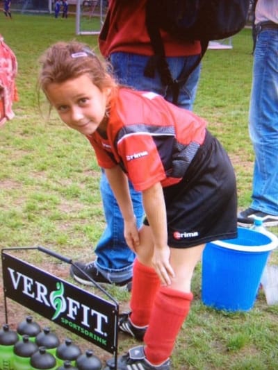 Lara Marti im Fussballtrikot auf dem Spielfeld, beugt sich über Wasserflaschenständer.