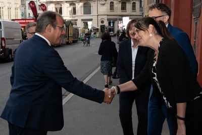 Zwei Personen geben sich auf einer städtischen Strasse die Hand, umgeben von anderen Personen.