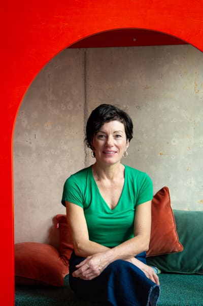 Andrea Grasser in einem roten Rahmen sitzt auf Kissen, grünes T-Shirt.