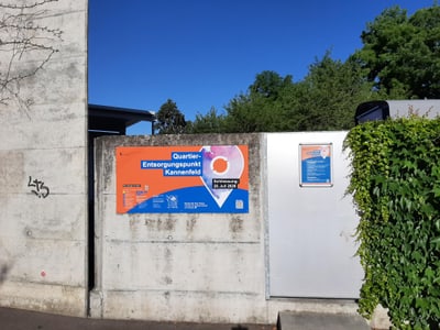 Betonwand mit buntem Plakat und grünem Laub.