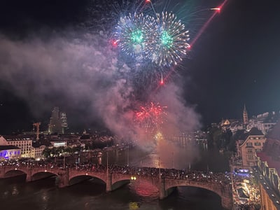 Feuerwerk über einer belebten Brücke in einer Stadt bei Nacht.
