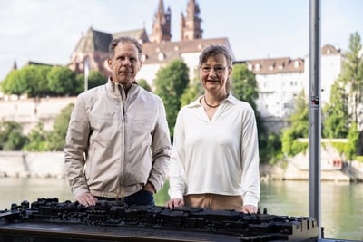 Daniel Aeschbach und Alexandra Binnenkade stehen vor einem Modell mit Fluss und Kirche im Hintergrund.