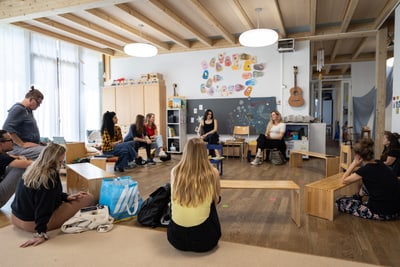 Gruppe von Menschen, die in einem Kinderzimmer im Kreis sitzen.