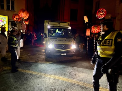 Die Sanität Basel fährt in Begleitung der Kantonspolizei Basel-Stadt durch eine Menschenmenge beim Morgestraich.