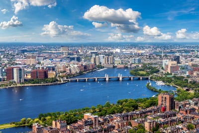 Stadtansicht mit Fluss und Brücke unter blauem Himmel.
