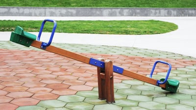 Wippe auf Spielplatz mit gepflastertem Boden.