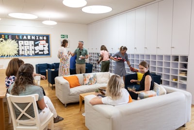 Menschen in einem Gemeinschaftsraum mit Sofas und Wanddekoration.