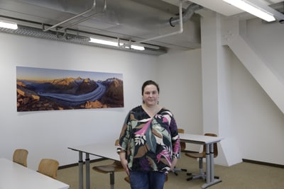 Aranka Sinko in einem modernen Klassenzimmer mit Berglandschaft-Bild an der Wand.