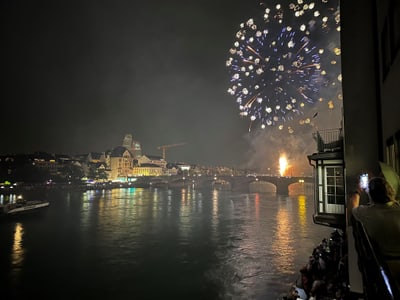 Feuerwerk über der Stadt bei Nacht mit Fluss im Vordergrund.