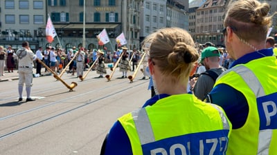 Polizisten beobachten eine Strassenszene mit Menschen und traditionellen Instrumenten.