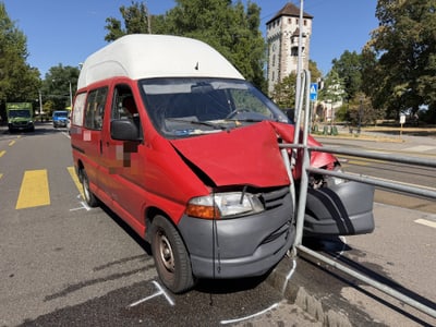 Roter Lieferwagen mit beschädigter Front auf der Strasse.