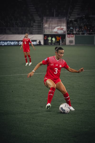 Lara Marti in rotem Trikot kontrolliert den Ball auf dem Spielfeld.