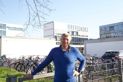 Mann steht vor Fahrrädern und Gebäuden im Freien.