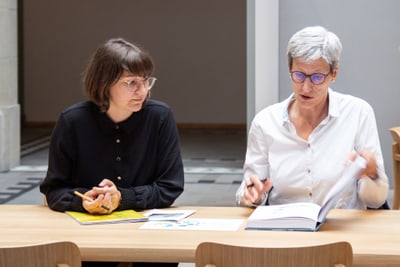 Valentina Heiss und Sabine Schärer bei einem Meeting am Tisch mit Büchern.