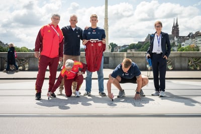 Gruppe von Personen auf einer Brücke, zwei knien und schreiben auf den Boden.