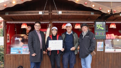 Menschen vor Süssigkeitenstand mit Zertifikat in der Hand.