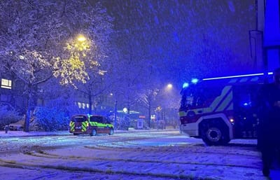 Schneebedeckte Strasse mit Einsatzfahrzeugen bei Nacht.",