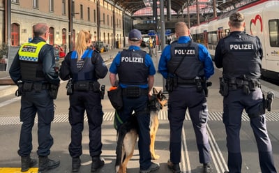 Polizisten und Hund auf Bahnsteig in Bahnhof.",