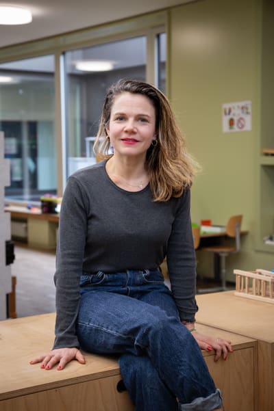 Frau sitzt lächelnd auf einem Tisch in modernem Raum.