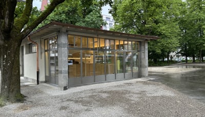 Kleines Gebäude mit grossen Fenstern im Park.