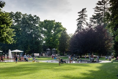 Menschen im Park mit Springbrunnen und Spielplatz.