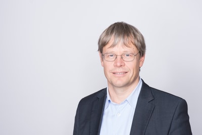Markus Neuenschwander in Anzug vor hellem Hintergrund.