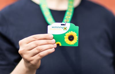 Person hält Sonnenblumenpass auf grünem Band.