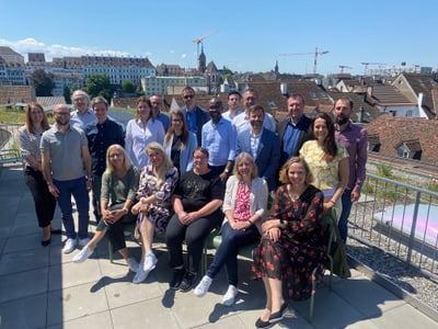 Gruppe von Menschen auf einer Dachterrasse mit Stadtblick im Hintergrund.