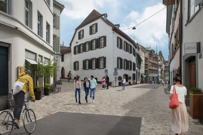 Menschen spazieren in einer Altstadtstrasse mit historischen Gebäuden.