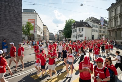 Menschenmenge in roter Kleidung bei einer Strassenparade in der Stadt.