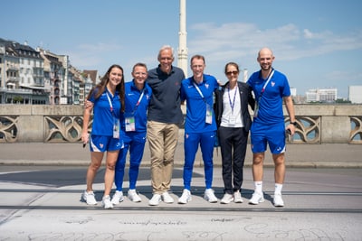 Gruppe von Menschen in Sportkleidung auf Brücke bei Sonnenschein.