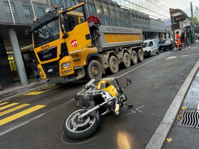 Gelber Lkw und umgestürztes Motorrad auf der Strasse.",