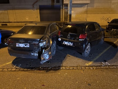 Zwei beschädigte Autos auf einem Parkplatz bei Nacht.",