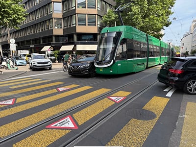 Grüne Strassenbahn kollidiert mit Auto auf städtischer Kreuzung.