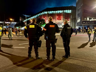 Polizisten auf der Strasse bei Nacht vor Gebäude mit rotem Licht.