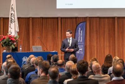 Mann hält Vortrag vor Publikum in einem Saal.