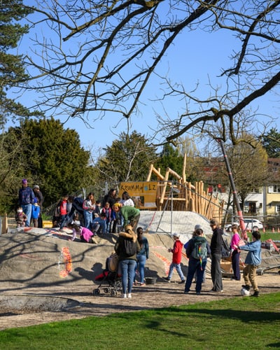 Menschen in einem belebten Park mit Spielgeräten.