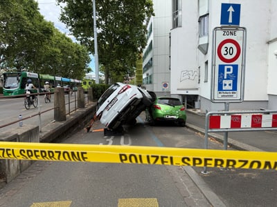 Ein Auto ist auf seiner Seite gekippt und ein anderes Auto steht daneben, mit einem Polizeiband im Vordergrund.