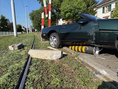 Auto auf Gehweg neben Strassenbahngleisen nach Unfall.