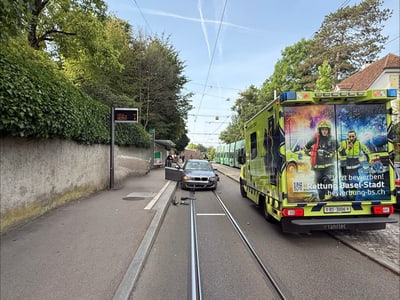 Auto blockiert Strassenbahngeleise neben Rettungsfahrzeug.