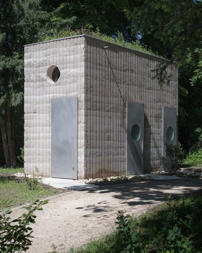 Kleines, modernes Gebäude im Wald mit runden Fenstern.