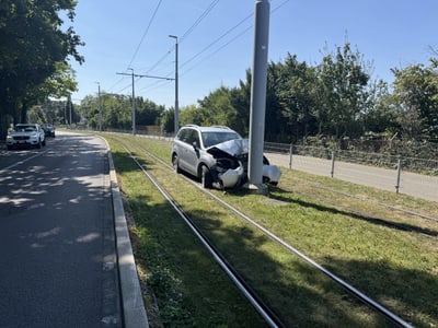 Auto nach Unfall mit Lichtmast neben Strassenbahngleisen.