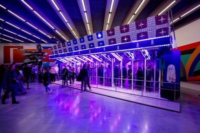 Leuchtende Installation mit lila und blauen Lichtern in einer Galerie mit Besuchern.