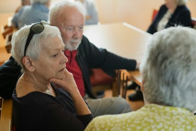 Ältere Menschen am Tisch in einem Gespräch.