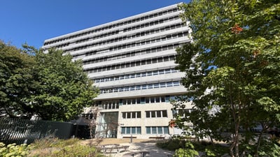 Mehrstöckiges Gebäude mit Bäumen im Vordergrund.