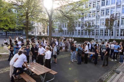Menschenmenge auf einem Schulhof bei Sonnenschein.