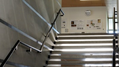 Moderne Treppe mit Wanduhren und Plakaten.