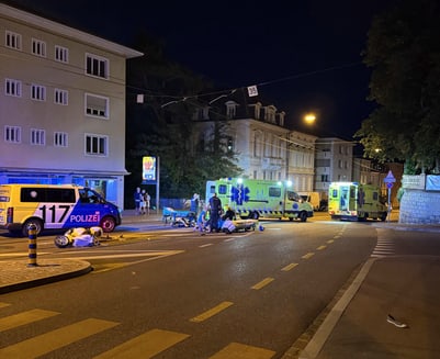 Nachtaufnahme einer Unfallstelle mit Polizei und Krankenwagen auf der Strasse.