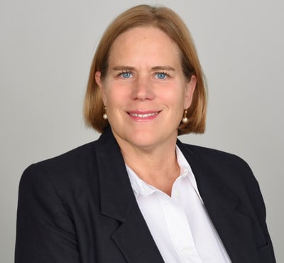 Porträt einer lächelnden Person in Anzugmantel und Hemd.